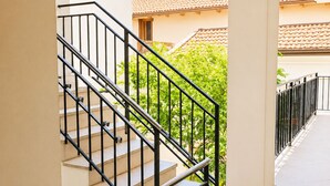A staircase with black railings leading to an outdoor area with a tiled floor and a view of a building with a tiled roof. - Casa Giorgia, a confortable and amazing place in centre of Cormons (Cormons)