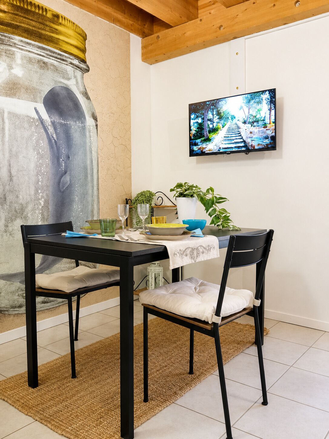 A dining area with a table, chairs, a TV, and a decorative wall.
