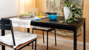 A dining area with a table set for two, a large wall mural of a jar, and a potted plant. - Casa Giorgia, a confortable and amazing place in centre of Cormons (Cormons)
