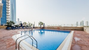 A rooftop swimming pool with a clear view of the city skyline in the background.