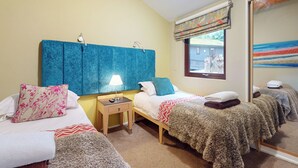 Habitación de hotel con dos camas, una mesita de noche con lámpara, una ventana con vistas y un espejo.