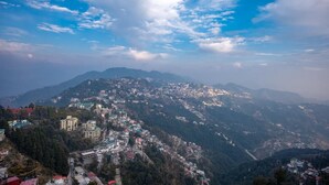 A mountainous town with buildings spread across the slopes, under a partly cloudy sky. - Syona Resort (Mussoorie)