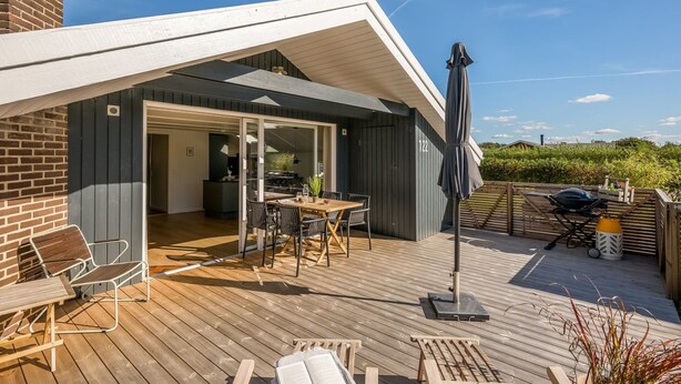 A modern outdoor deck with a dining area, a barbecue setup, and a covered seating area. - "Thamina" - 200m to the fjord by Interhome (Hemmet)