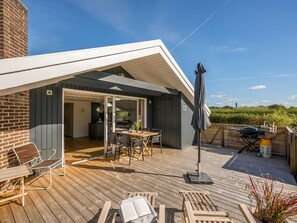 A modern outdoor deck with a dining area, a barbecue setup, and a covered seating area. - "Thamina" - 200m to the fjord by Interhome (Hemmet)