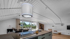 A modern kitchen with a large island, a built-in oven, and a dining area with a view of the outdoors. - "Thamina" - 200m to the fjord by Interhome (Hemmet)