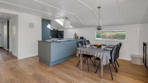 A modern kitchen with a central island, a dining area with a table and chairs, and a view through a window. - "Thamina" - 200m to the fjord by Interhome (Hemmet)