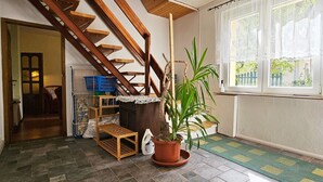 A staircase with wooden railings, a potted plant, a lace tablecloth, and a window with a view of greenery.