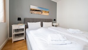 A hotel room with a bed, two bedside tables, a nightstand, a desk, and a wall-mounted picture. - Binz - WE Prorer Wiek 1 - Apartment for 4 persons near the beach and the center (Binz)
