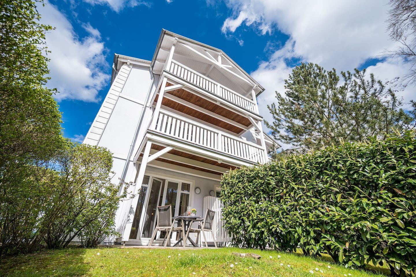 A two-story building with a balcony, a covered porch, and a well-maintained garden.