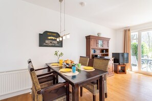 Un comedor con una mesa de madera oscura, sillas de mimbre y un letrero en la pared.