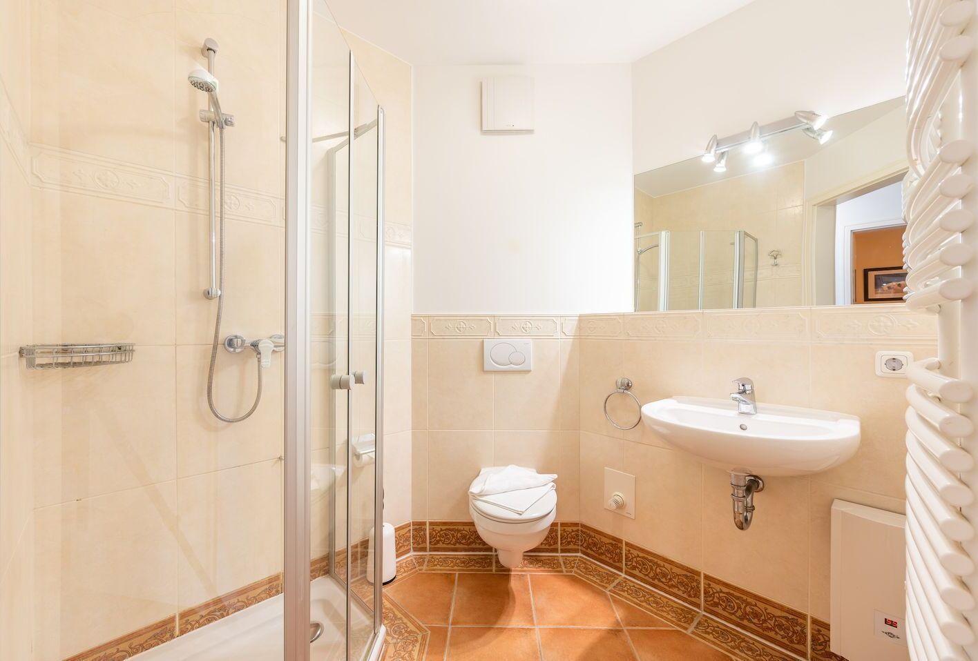 Ein Badezimmer mit einer Duschkabine, einem weißen Waschbecken und einer Toilette.