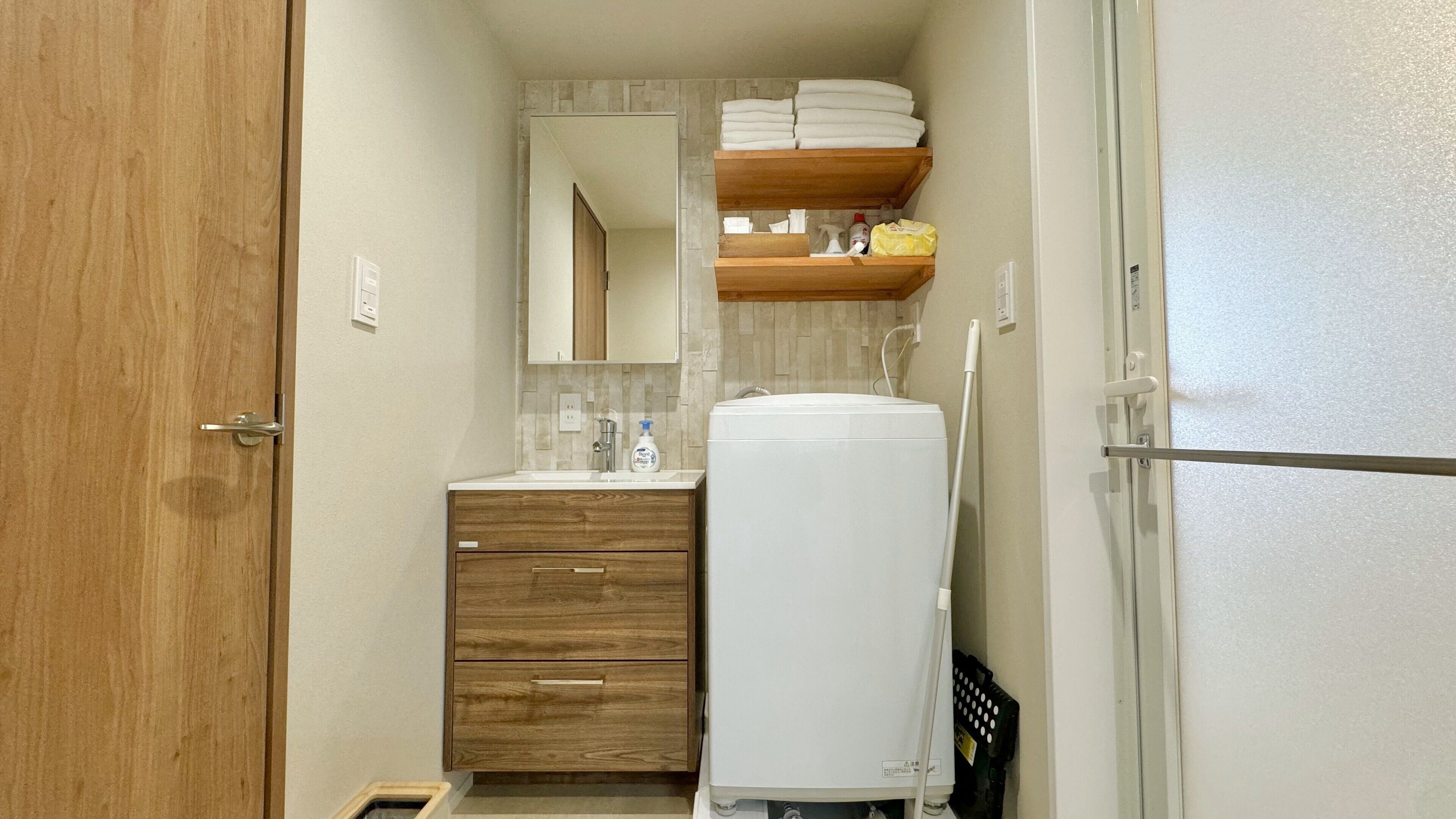 Une petite salle de bain avec un meuble-lavabo en bois, un lavabo blanc, un miroir et un porte-serviettes au-dessus du plan de travail.