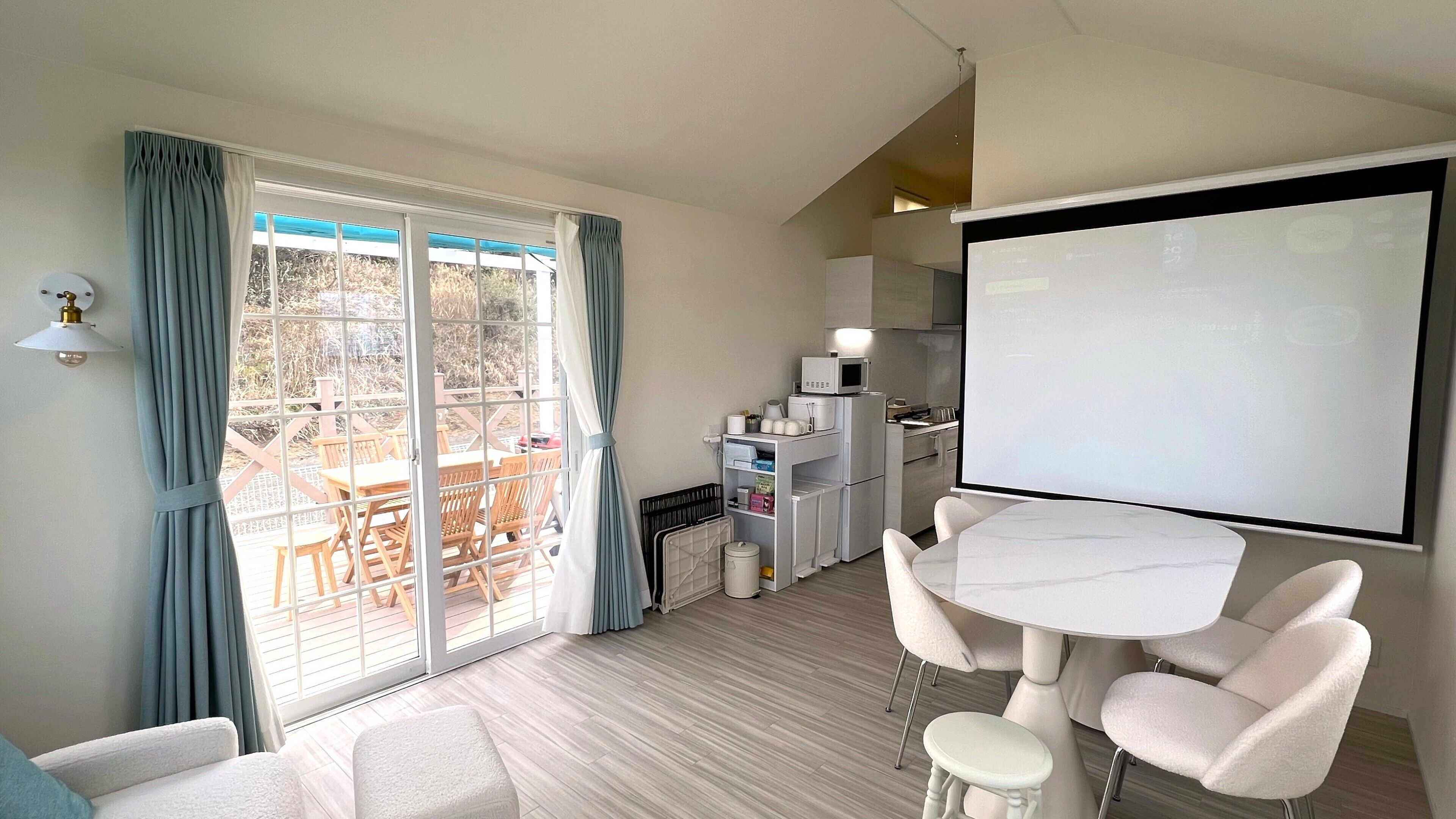 A modern room with a dining area, a kitchen, and a balcony with outdoor furniture.