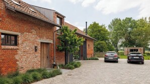 A brick building with a paved driveway and parked cars. - BARN - Waasmunster (Waasmunster)