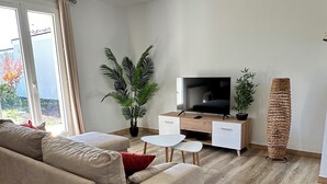 Un saló modern amb un sofà, televisió i plantes.