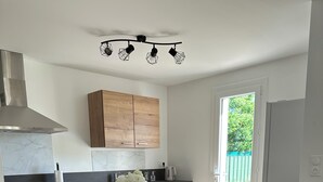 Una cuina moderna amb una illa central, armaris de fusta, una campana extractora d'acer inoxidable i una zona de menjador amb tamborets.