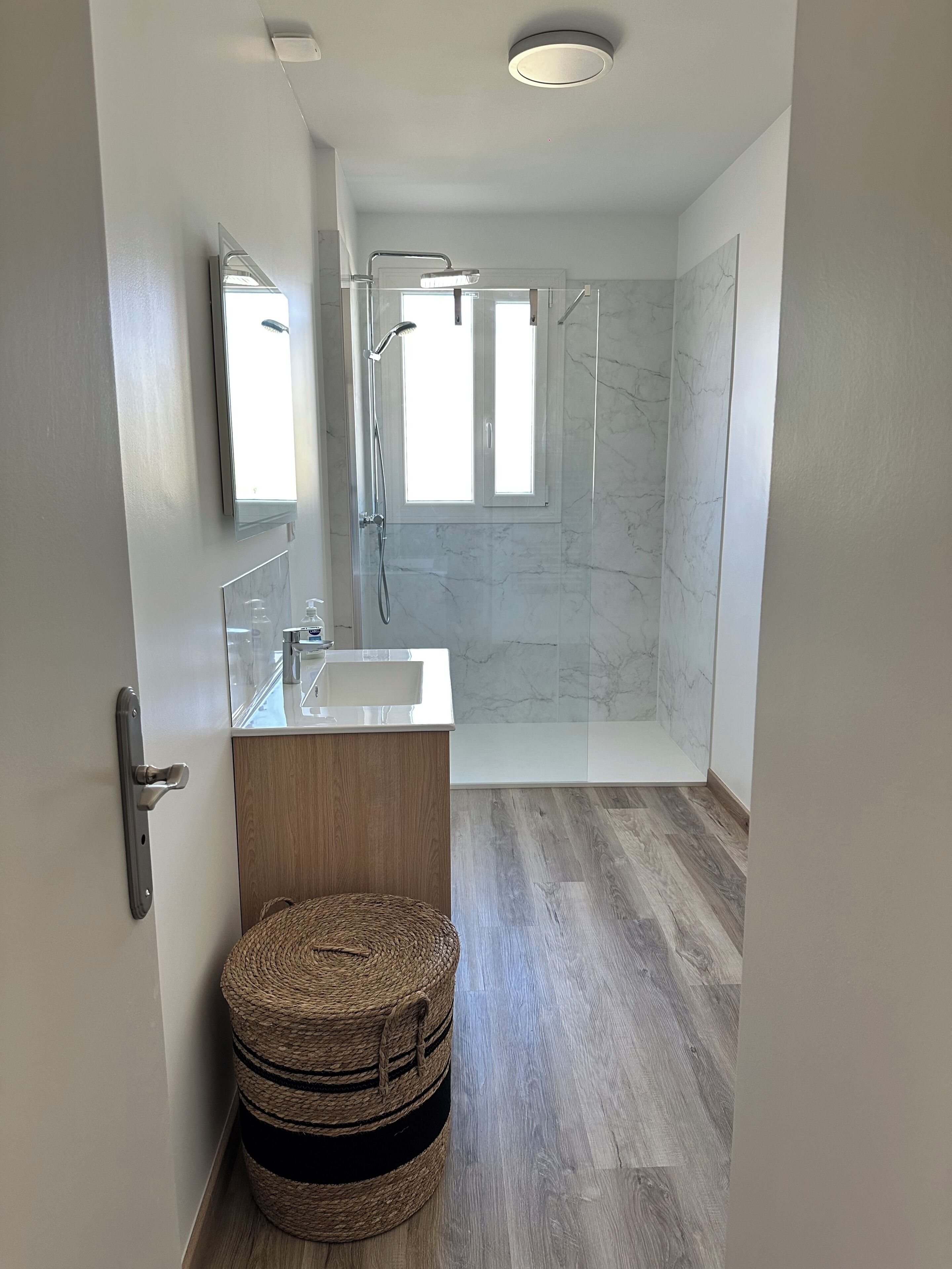 Un baño moderno con ducha, lavamanos y espejo.