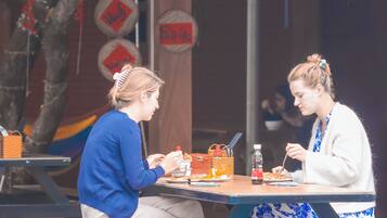 Two people dining at an outdoor table with a basket and a bottle of sauce.