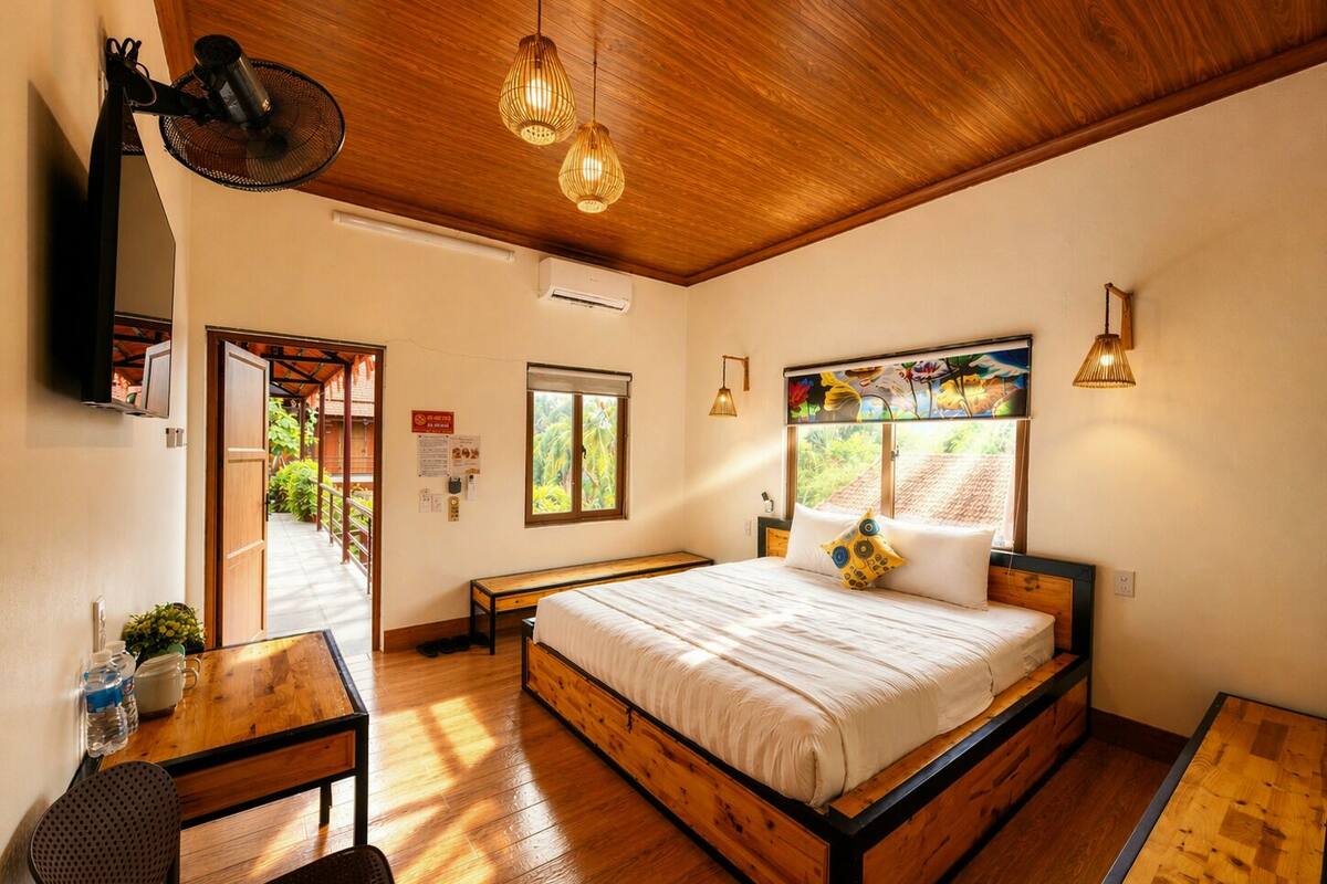 Un dormitorio con una cama de madera, un escritorio, una silla, una ventana con vistas y un ventilador de techo.