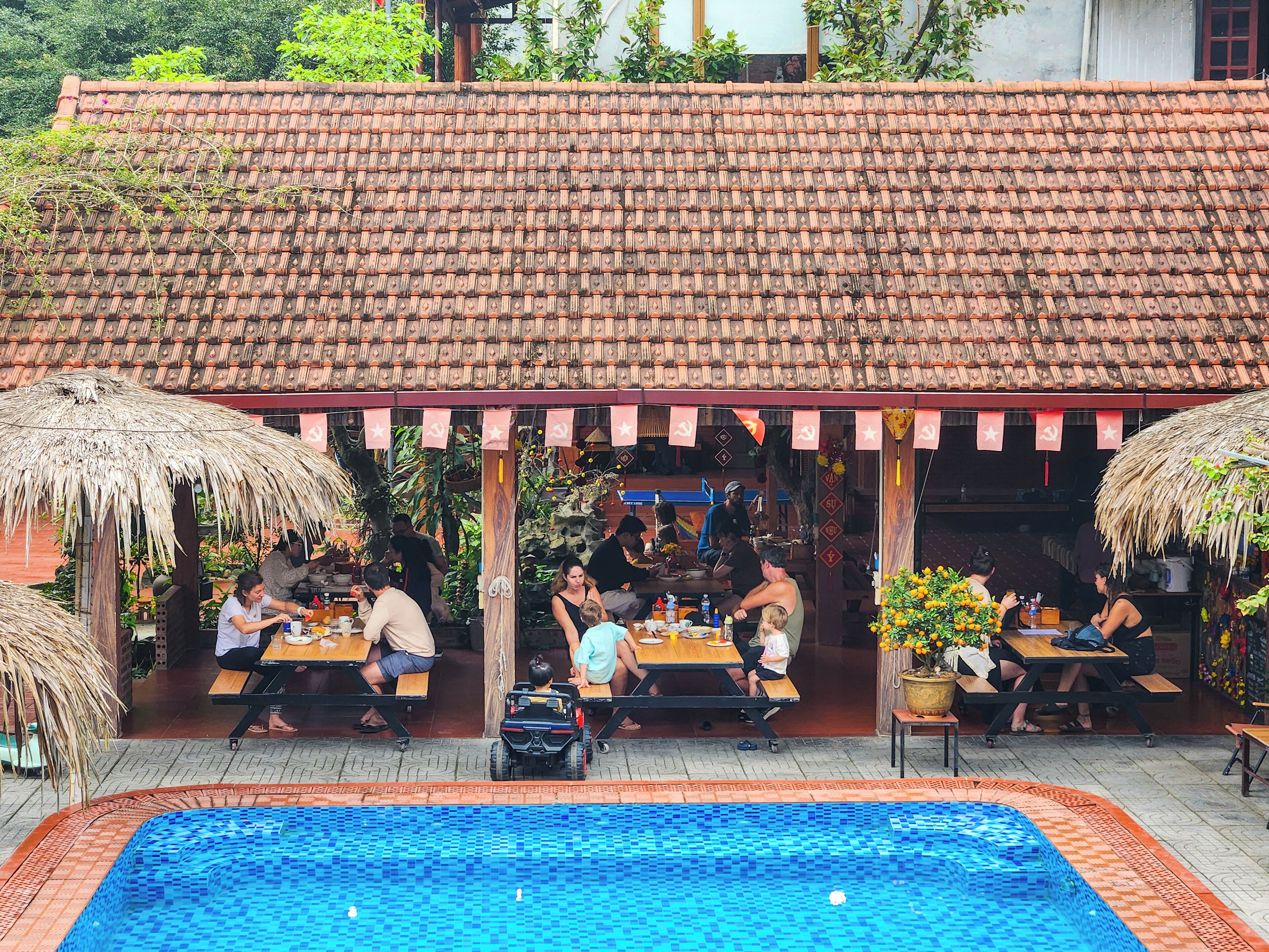 An outdoor dining area with a tiled roof and a pool.