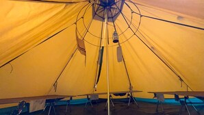 A yellow tent with a central pole, guy lines, and a lantern hanging from the top. - Pure nature in the "Skogsanda" tipi - your retreat in Sweden's wilderness (Arvika)