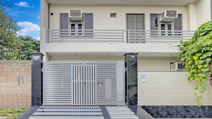 Een gebouw met twee verdiepingen, een hek, airconditioning en een balkon.