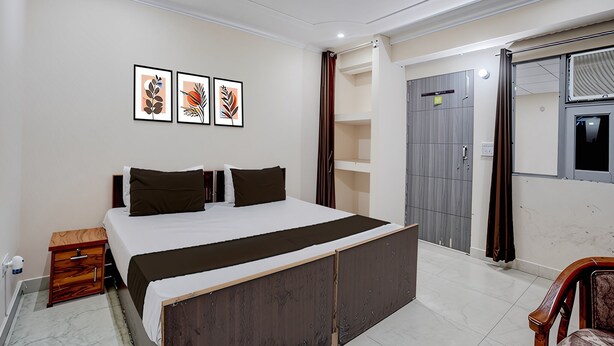 Een slaapkamer met een bed, een houten nachtkastje, een kledingkast en een raam met gordijnen.