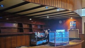 A wooden reception desk with a glass display case, a clock, and a poster on the wall. - Asis Hotel Eldoret  (Eldoret)