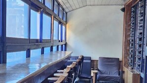 A bar area with wooden stools and a long counter, a single chair, and a tiled floor. - Asis Hotel Eldoret  (Eldoret)