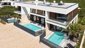 A modern two-story building with a rooftop pool area, including two swimming pools and a sun terrace. - Villa Yana with Pool and Sea View (Medulin)