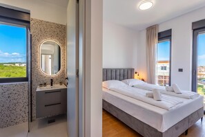 A modern bedroom with a large bed, a bedside table, a mirror, and a view of the outdoors. - Villa Emma With Pool and sea view (Medulin)