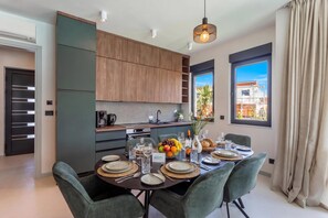 A modern kitchen with built-in appliances, a dining area with a table set for four, and a view of the outside through large windows. - Villa Emma With Pool and sea view (Medulin)