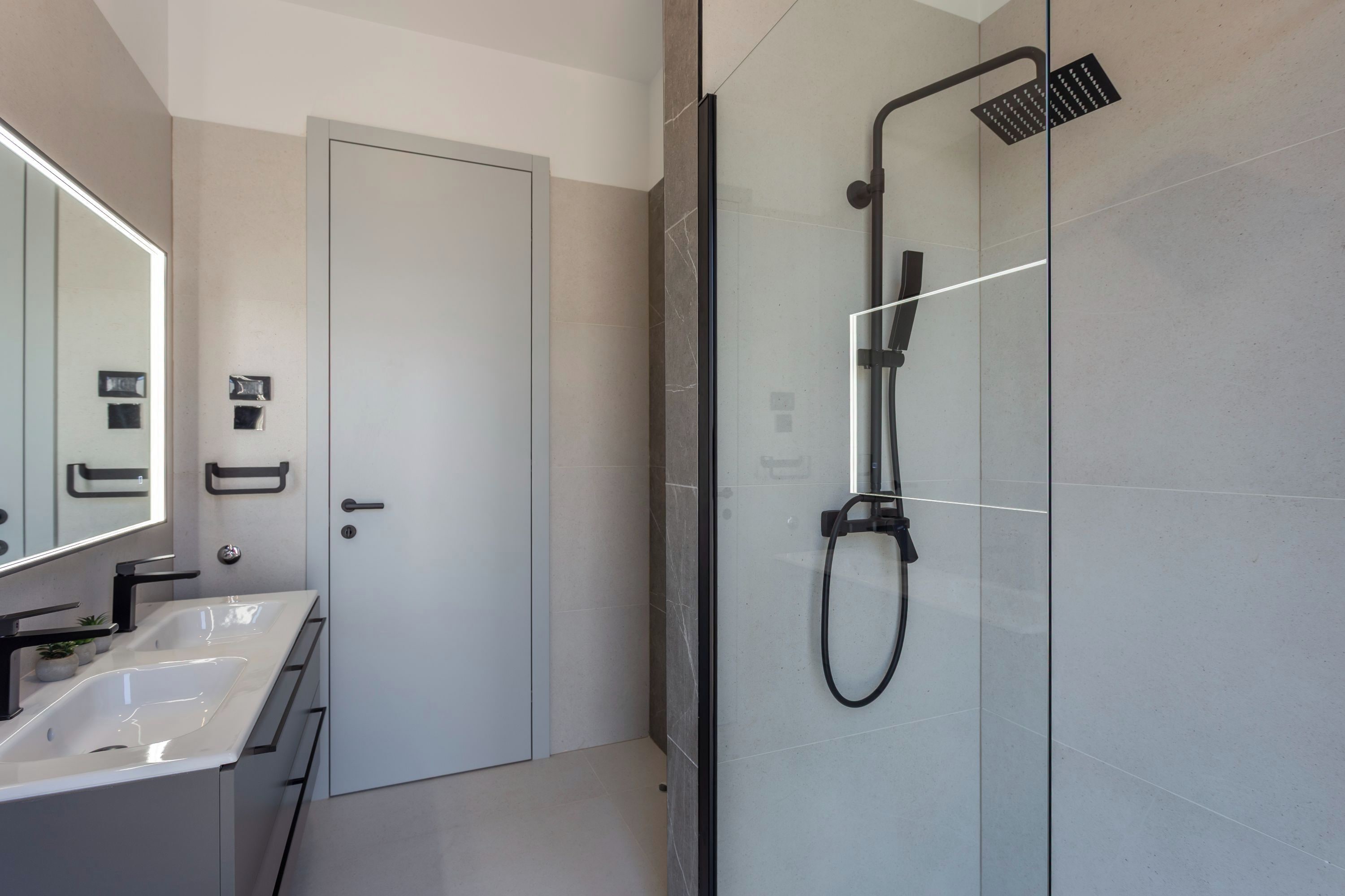A modern bathroom with a glass shower enclosure, a double sink vanity, and a large mirror.