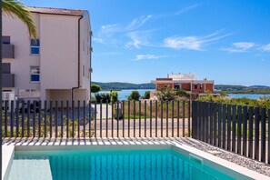 A swimming pool with a view of a body of water and buildings in the background. - Villa Emma With Pool and sea view (Medulin)