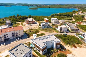 Μια παραθαλάσσια οικιστική περιοχή με σύγχρονα κτίρια, μια καθαρή, γαλάζια θάλασσα και ένα μικρό νησί.