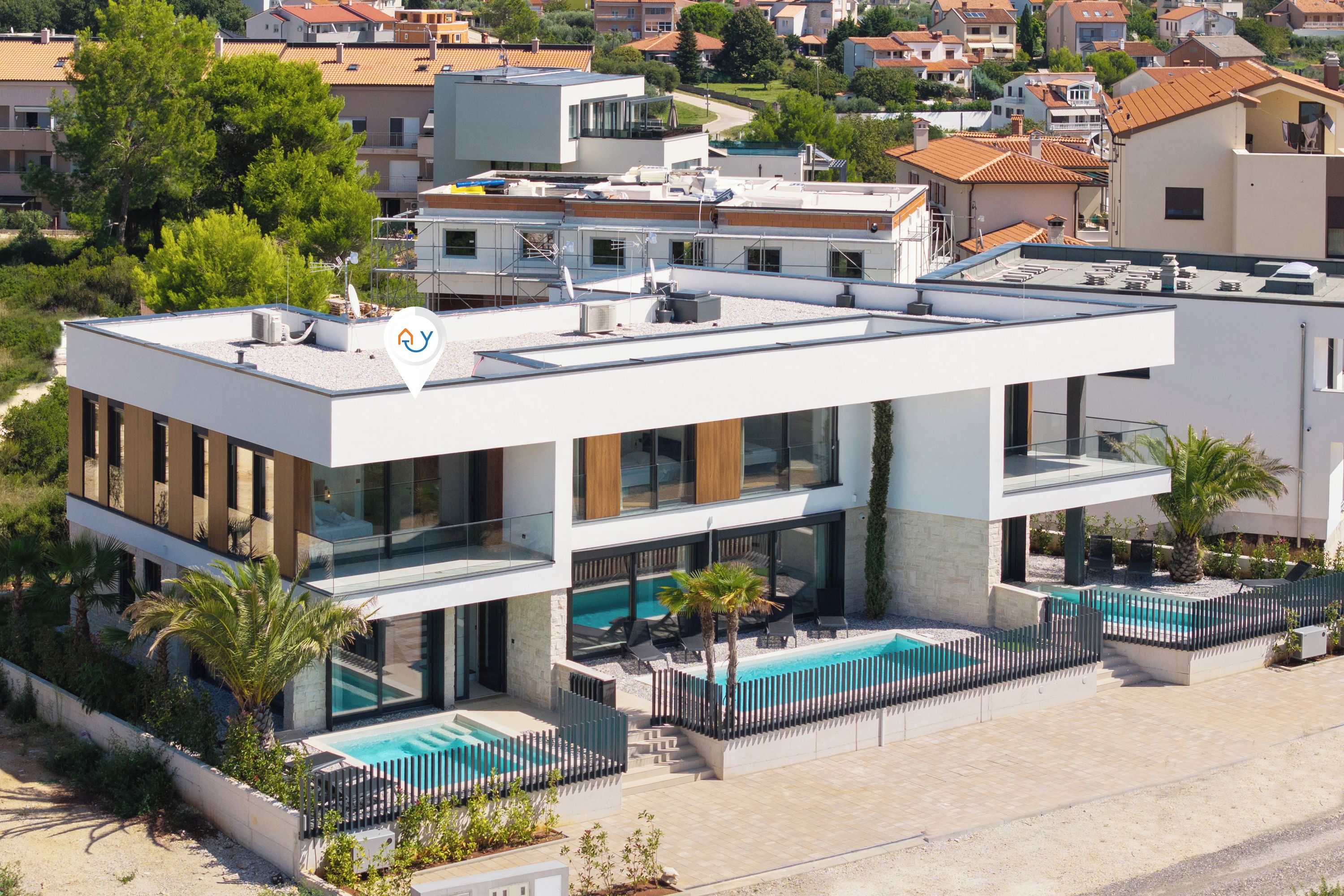A modern two-story building with a rooftop pool, large windows, and a flat roof.