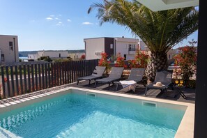 A swimming pool with lounge chairs and a palm tree. - Villa Petra with Pool and Sea View (Medulin)
