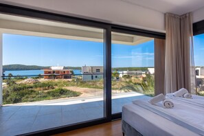 A bedroom with a large window, a bed, and a view of a coastal landscape. - Villa Petra with Pool and Sea View (Medulin)