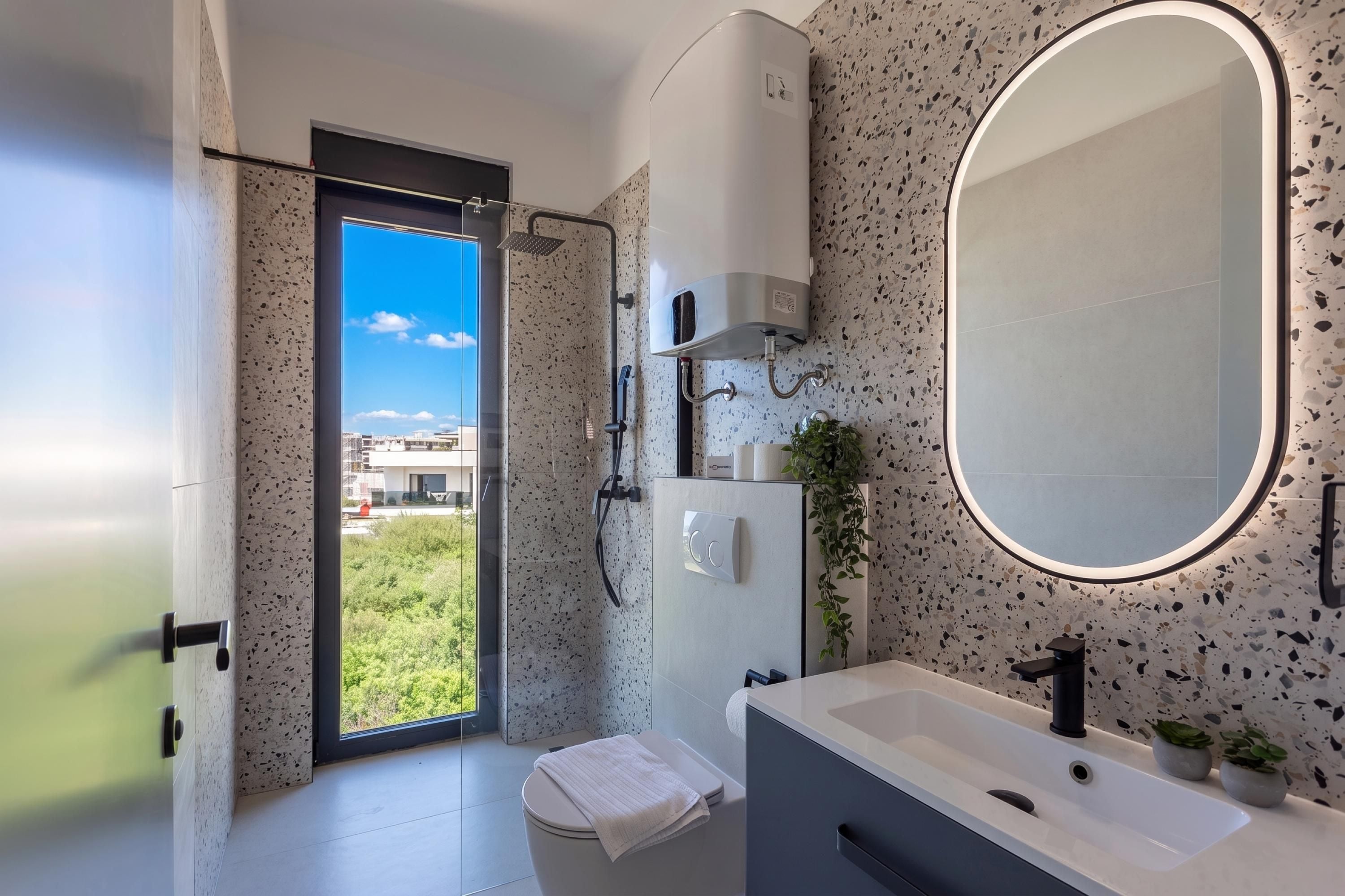 Ein modernes Badezimmer mit einem großen Spiegel, einer Dusche und einem Waschbecken.