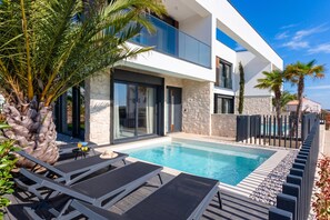 A modern two-story house with a swimming pool, lounge chairs, and palm trees. - Villa Petra with Pool and Sea View (Medulin)