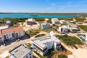 A coastal residential area with modern buildings, a clear blue sea, and a small island in the distance. - Villa Petra with Pool and Sea View (Medulin)