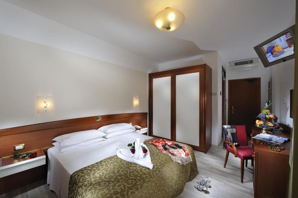 Een hotelkamer met een bed, een bureau, een stoel, een televisie en een kledingkast.