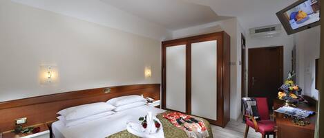 A hotel room with a bed, bedside table, TV, desk, and a chair.