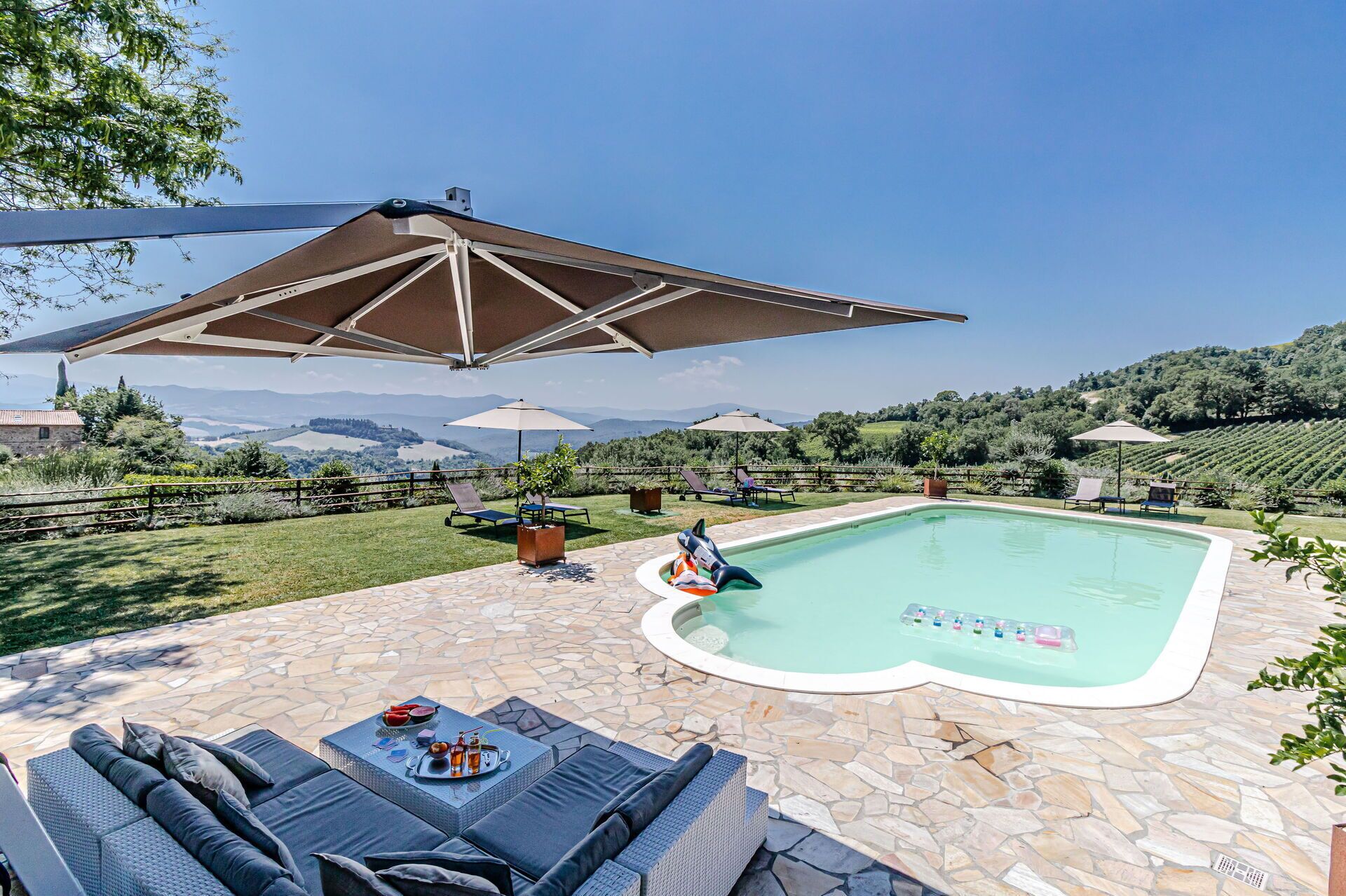 Un espace piscine avec des chaises longues, une table avec des boissons et des parasols.