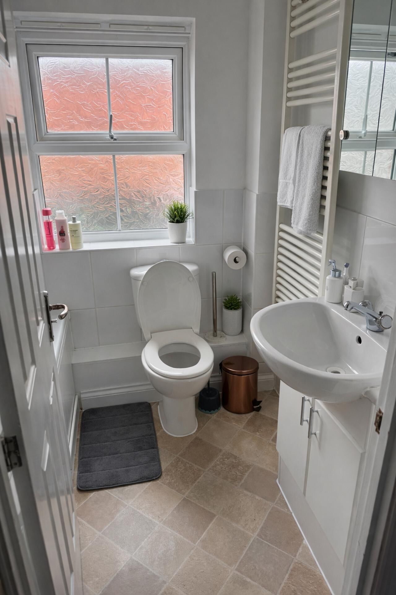 A bathroom with a toilet, sink, and window.