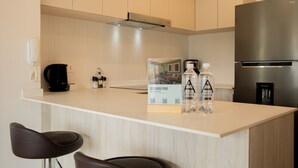 A modern kitchen with a white countertop, stainless steel appliances, and two bar stools. - w* | Amazing & Cozy 2BR w/ Balcony in San Isidro (Lima)