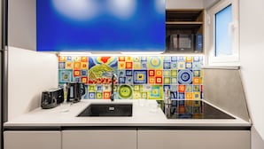 A modern kitchen with a large blue backsplash, a stainless steel microwave, and a coffee maker. - Pop House in the Heart of Sanita by Wonderful Italy (Naples)