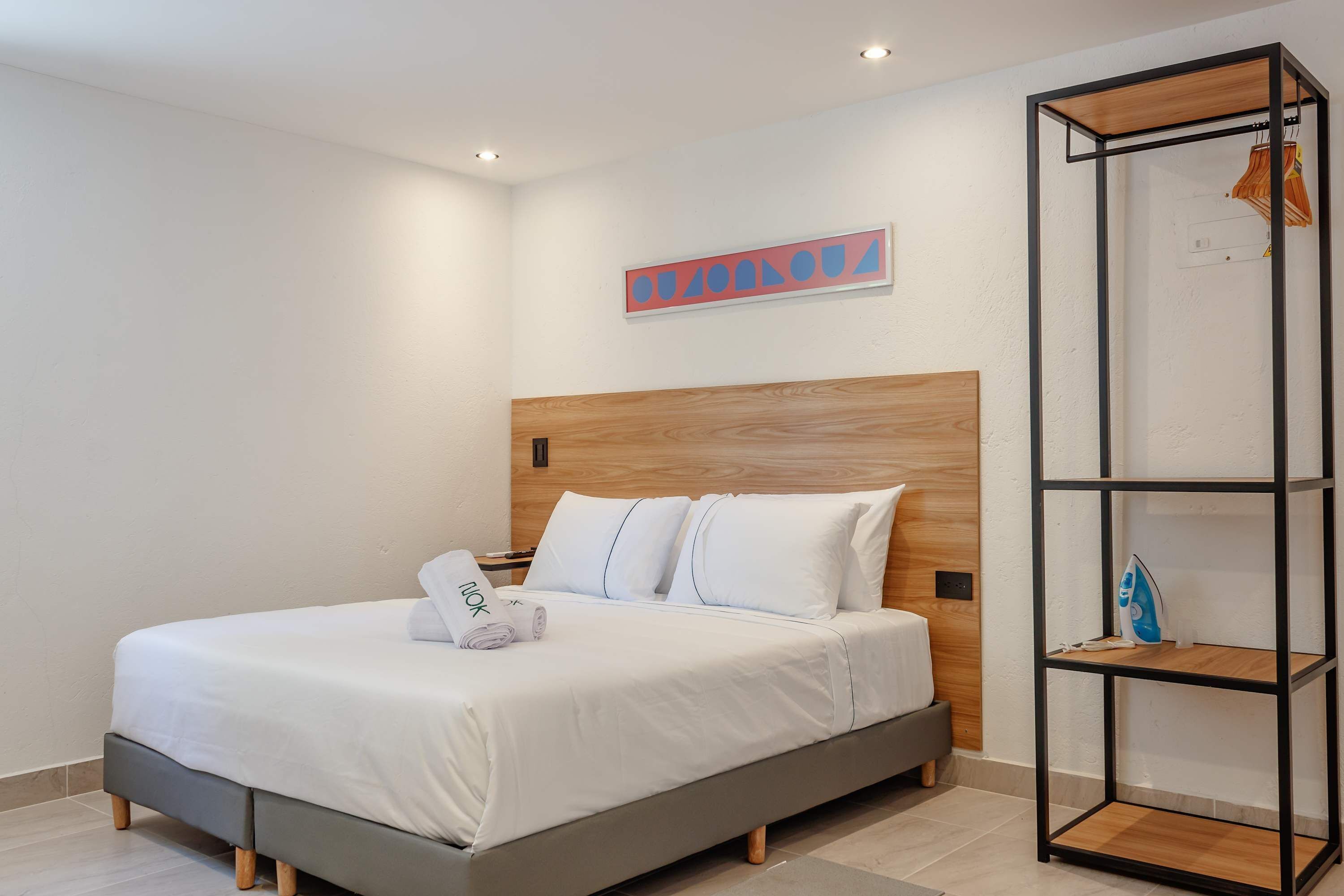 Ein modernes Schlafzimmer mit einem Holzkopfteil, einem Bett mit weißen Bettwäsche und einer eingebauten Regaleinheit.