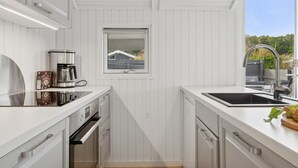 A modern kitchen with white cabinetry, stainless steel appliances, a window with a view, and a sink with a faucet.