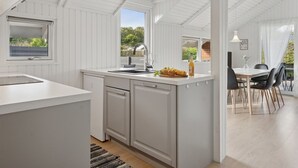 A modern kitchen with white cabinetry, a large island, and a dining area with a table and chairs.